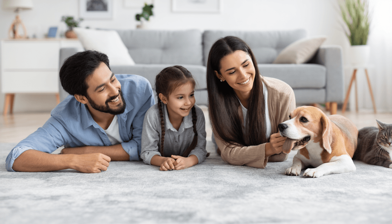 Famiglia felice che osserva cane e gatto giocare insieme nel salotto